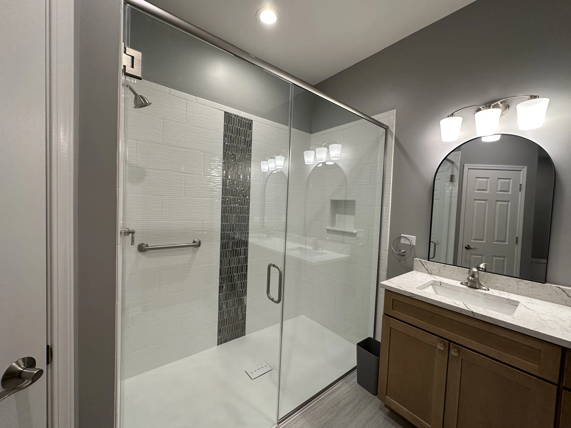 Bathroom remodel with a glass walk-in shower and wood vanity by EZ Custom Homes