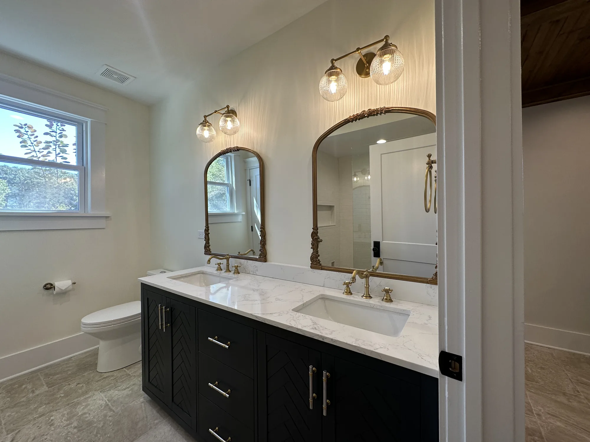 Bathroom remodel with a black double vanity and arched mirrors by EZ Custom Homes