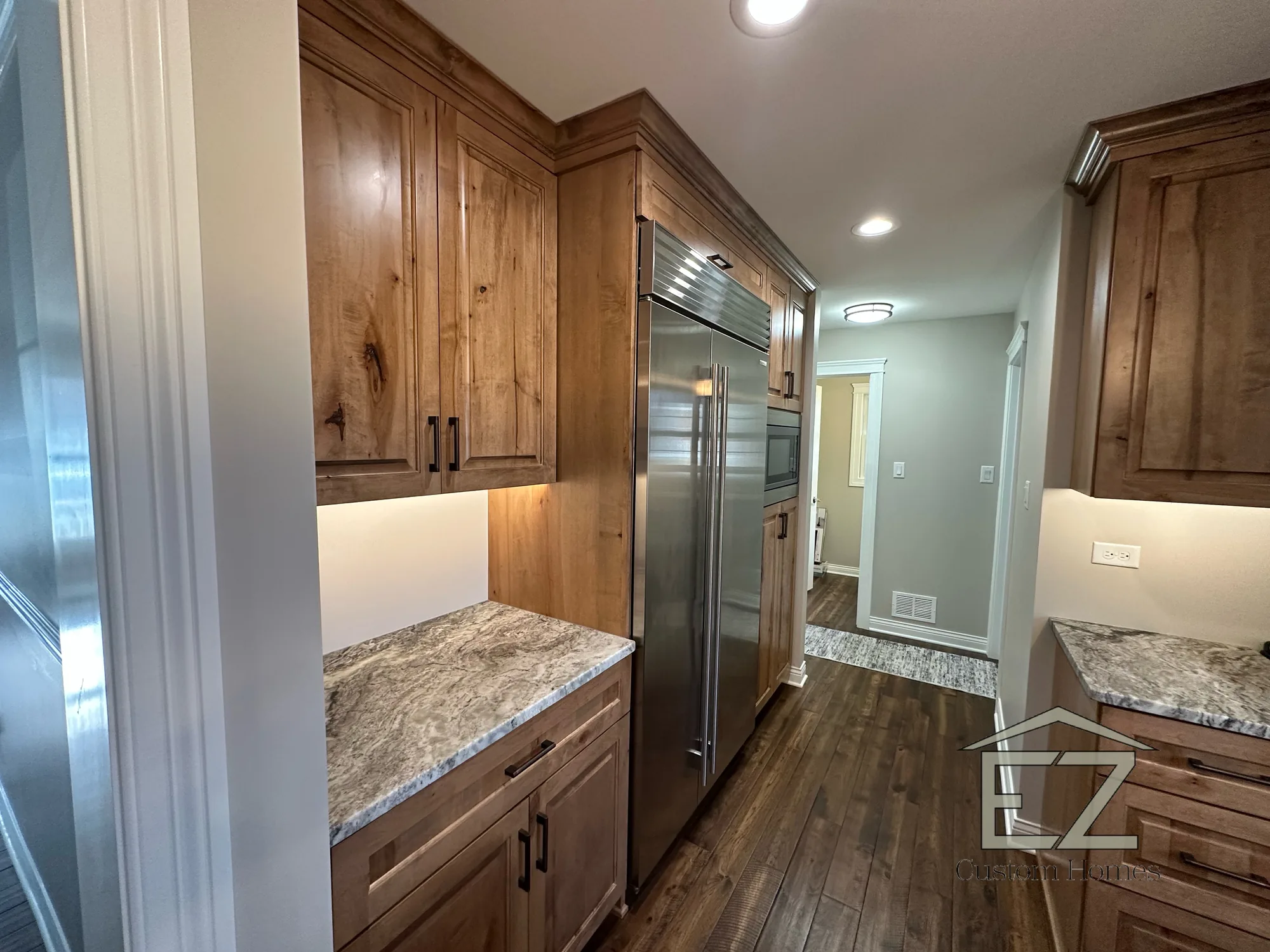 Kitchen with custom wood cabinetry and stainless appliances by EZ Custom Homes