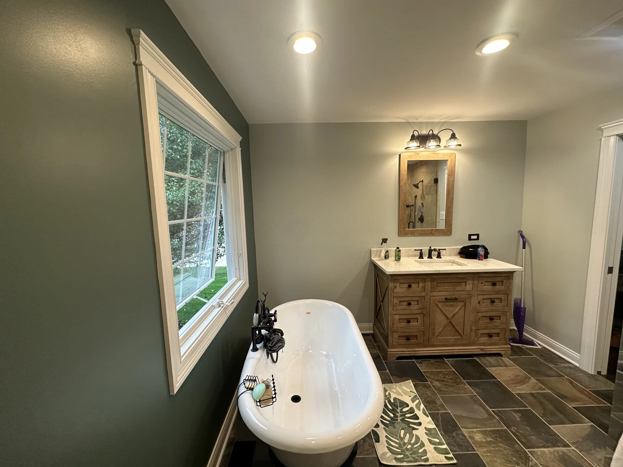 Bathroom remodel with a clawfoot tub and a wood vanity by EZ Custom Homes